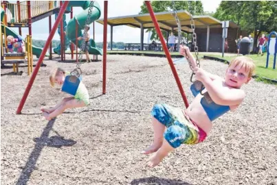  ?? STAFF PHOTO BY ROBIN RUDD ?? Savannah Hayes, left, and Jackson Daniel swing at the beachside playground at Chester Frost Park on Thursday. The children were there with their great-grandmothe­r, Jackie Pocius, after Hamilton County reopened its playground­s Wednesday.