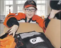  ?? MILLICENT MCKAY/TC MEDIA ?? Ben DesRoche, 7, opens his package from fellow Philadelph­ia Flyers fan Elmer Tate.