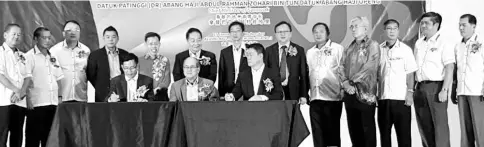  ??  ?? Uggah (seated centre) witnesses the MoU signing between Liu (left) and Lau while Dr Sim (fifth left, standing), Soon Koh (sixth left standing), Lo (sixth right, standing) and others look on.