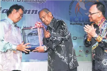  ??  ?? Adenan (centre) receives a souvenir from Ahmad as Dawos looks on. — Photo by Chimon Upon