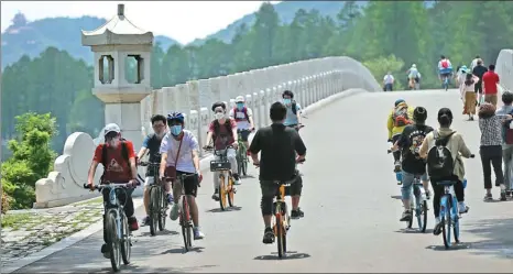  ?? ZHOU GUOQIANG / FOR CHINA DAILY ?? Cyclists and pedestrian­s traverse a bridge at East Lake on Sunday in Wuhan, Hubei province, the hardest-hit region from the COVID-19 pandemic in China. Locals enjoyed their first public holiday since the monthslong regional lockdown was lifted.