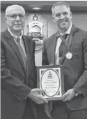  ?? ALISON JENKINS/ LOCAL JOURNALISM INITIATIVE REPORTER ?? Dr. Wassim Salamoun, left, holds the plaque honouring his co-worker Paul Young at Summerside city hall on Oct. 13. Salamoun read the citation awarding Young the mayor's Medal of Honour.