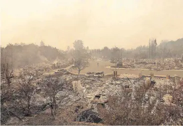  ?? [AP PHOTO] ?? A man walks down a street Monday between the wreckage of houses destroyed by fire in Santa Rosa, Calif.