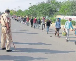  ?? YOGENDRA KUMAR/HT PHOTO ?? Stranded migrant workers head to a temporary shelter home inside Tau Devi Lal Stadium, under the watchful eyes of Gurugram police, on Friday.