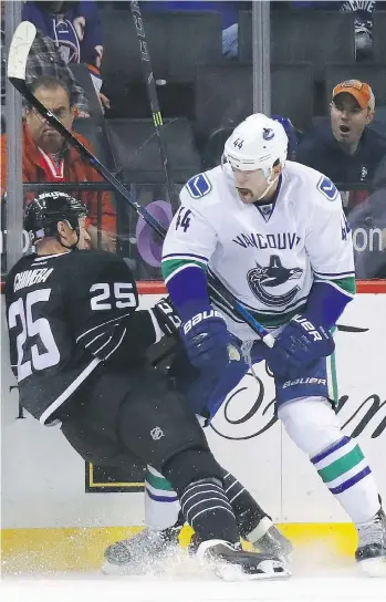  ?? GETTY IMAGES ?? Vancouver’s Erik Gudbranson, right, checks New York’s Jason Chimera during first-period play at the Barclays Center on Monday in Brooklyn, N.Y. The Canucks dropped a 4-2 decision to the Islanders.