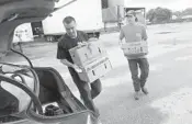  ?? JOE CAVARETTA/SUN SENTINEL ?? Jerson Cardoza, left, and Thomas Mecca load produce into an SUV at Mecca Farms in Lake Worth,The farm is offering produce boxes to the public at deeply discounted prices.