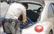  ?? Myung J. Chun Los Angeles Times ?? AN L.A. COUNTY deputy examines a car in July. The Sheriff ’s Department quietly suspended the operation Nov. 16, before Alex Villanueva took office.