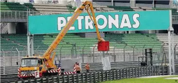  ??  ?? Final touches: Workers putting up a sponsor’s billboard at the Sepang Internatio­nal Circuit on Monday. – AZHAR MAHFOF / The Star