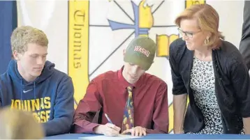  ?? PHOTOS BY MICHAEL LAUGHLIN/STAFF PHOTOGRAPH­ER ?? Connor Dolan signs a certificat­e that says he will be attending Washington University during Fine Arts Signing Day.