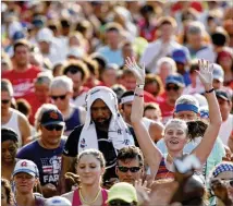  ?? CONTRIBUTE­D BY JASON GETZ ?? A runner waves from the sea of humanity that was the 2016 AJC Peachtree Road Race. This year’s event will funnel 60,000 runners through the heart of Atlanta on Wednesday.