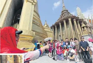  ??  ?? ABOVE Chinese tourists pose for pictures at the Temple of the Emerald Buddha in Bangkok.