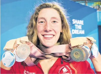  ?? CP PHOTO ?? Taylor Ruck holds up her eight swimming medals at the Commonweal­th Games.