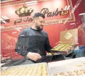  ?? ?? Crown Pastries co-owner Ismail Alsalha fills a box with assorted pastries at his flagship shop in Scarboroug­h.