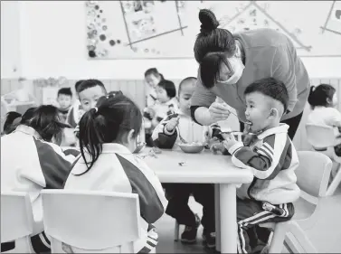  ?? XINHUA ?? A teacher feeds a boy at a kingdergar­ten in Shishi, Fujian province.