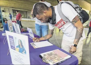  ?? Jim franco / Special to the times union ?? deshawn Smith fills out paperwork on Saturday at the Legal Shield during a Youth Job fair sponsored by Albany Snug and the team Hittaz Boxing Club at the Swinburne Park in Albany.