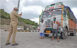  ?? — PTI ?? A policeman clicks a photo of truck drivers as the security has been enhanced ahead of the Independen­ce Day at the entry point of Jammu on Saturday.