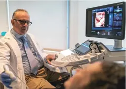  ??  ?? Dr. Jacques Abramowicz performs an abdominal ultrasound on a patient.