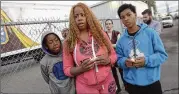  ?? SILVIA FLORES / THE FRESNO BEE ?? (From left) Va’Ron Mitchell, his aunt Deshunna Ricks and his cousin A’Marian Trujillo, all of Fresno, hold candles with community members and faith leaders during a prayer and vigil in Fresno, Calif.