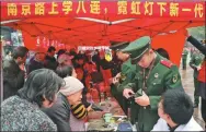  ??  ?? Soldiers of the squad provide voluntary services to Shanghai residents on the city’s Nanjing Road.