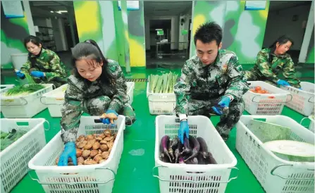  ?? PENG ZHAOZHI / XINHUA ?? Chen Kunyuan (second from right) and some of his employees sort vegetables before delivering them to customers in Nanchang, Jiangxi province.