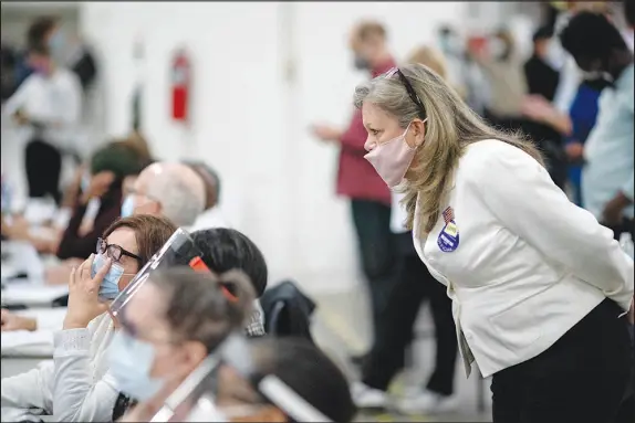  ?? DAVID GOLDMAN / AP FILE (2020) ?? A Republican election challenger, at right, watches over election inspectors as they examine a ballot as votes are counted into the early morning hours, Nov. 4, 2020, at the central counting board in Detroit. Election officials across the country are bracing for a wave of confrontat­ions in November as emboldened Republican poll watchers, many embracing former President Donald Trump’s conspiracy theories about the 2020 election, flood polling places for the general election.