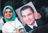  ?? XINHUA ?? A supporter of Hosni Mubarak holds up his pictures on Thursday as he is to be transferre­d to a court in Cairo, Egypt.