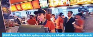  ?? — AFP ?? MOSCOW, Russia: In this file photo, employees serve clients in a McDonald’s restaurant on Pushkin square in Moscow. American fast-food giant McDonald’s will exit the Russian market and sell its business in the increasing­ly isolated country, the company said May 16, 2022.