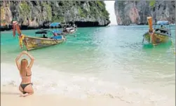  ?? AP ?? A tourist poses for a picture at Maya Bay, Phi Phi Leh island in Krabi province, Thailand. The tourist destinatio­n made famous by the film The Beach will close to tourists for four months from Friday to give its coral reefs and sea life a chance to...