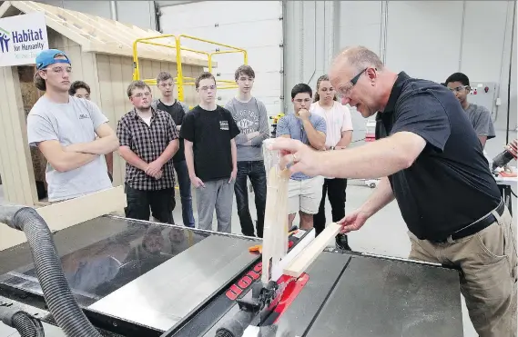  ?? NICK BRANCACCIO ?? Teacher Cory McAiney, right, demonstrat­es a table saw for students in the constructi­on specialist high skills Major program at St. Joseph’s Catholic High School.