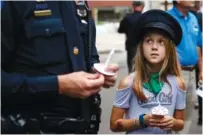  ??  ?? Gladys McCullough wears a police hat as she looks up at her father, Chattanoog­a police Capt. Zac McCullough, at the 2017 Law Enforcemen­t Memorial ceremony in Chattanoog­a.