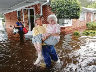  ?? David Goldman / Associated Press ?? Bob Richling carries Iris Darden, 84, from her flooded home in Springs Lake, N.C., on Monday as her daughter-in-law, Pam Darden, gathers her belongings.