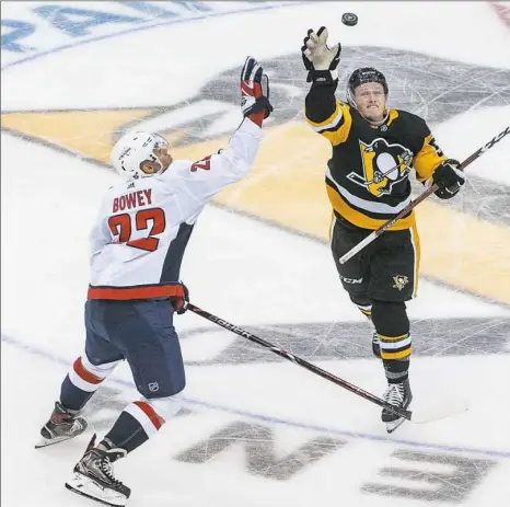  ??  ?? Washington’s Madison Bowey, left, and Jake Guentzel attempt to knock down the puck midway through the season opener Thursday night at PPG Paints Arena.