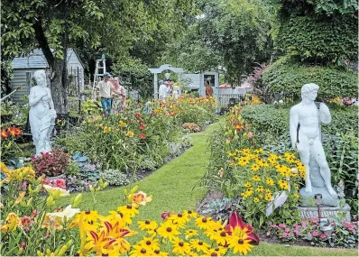  ?? ?? Formal beds brimming with lush daylilies and an eclectic mix of garden ornamentat­ion are featured in the garden of this historic home.