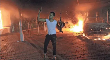  ?? AFP/GETTY IMAGES ?? A man waves his rifle as buildings and cars are engulfed in flames inside a U.S. compound in Benghazi, Libya, on Sept. 11, 2012.