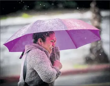  ?? Allen J. Schaben Los Angeles Times ?? THE SECOND in a string of five back-to-back storms through Thursday saturated the Southland on Monday. Above, a woman uses an umbrella as she walks along the sidewalk in the rain in Los Angeles.