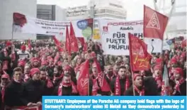  ??  ?? STUTTGART: Employees of the Porsche AG company hold flags with the logo of Germany’s metalworke­rs’ union IG Metall as they demonstrat­e yesterday in front of their plant in Stuttgart, southern Germany. — AFP