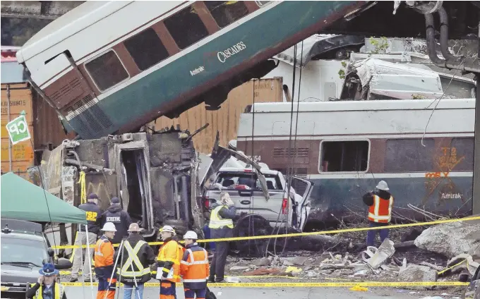  ?? AP PHOTO ?? TRANSIT TRAGEDY: Cars from an Amtrak train that derailed above lay spilled onto Interstate 5 alongside smashed vehicles yesterday, in DuPont, Wash. The Amtrak train making the first-ever run along a faster new route hurtled off the overpass yesterday...