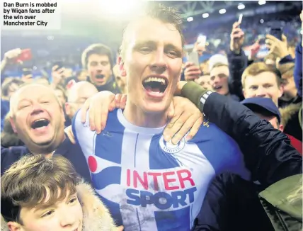  ??  ?? Dan Burn is mobbed by Wigan fans after the win over Manchester City