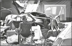  ?? ASSOCIATED PRESS ?? A HOMELESS MAN SITS BY HIS BELONGINGS at the Lots, a county-run outdoor encampment in downtown Phoenix, on June 24. Homeless people are among the most vulnerable population­s in the COVID-19 pandemic, yet they’re largely invisible victims.