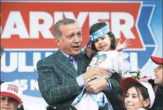  ?? Lefteris Pitarakis/Associated Press ?? Turkey’s President Recep Tayyip Erdogan holds a young girl in Istanbul on Saturday during his last rally ahead of Sunday's referendum.