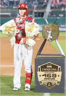  ?? Yonhap ?? Choi Jeong of the SSG Landers poses next to a commemorat­ive plaque after hitting a record 468th career home run during a KBO game against the Lotte Giants at Sajik Baseball Stadium in Busan, Wednesday.