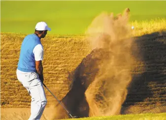  ?? Stuart Franklin / Getty Images ?? Tiger Woods blasts out of a bunker on the 14th hole at Carnoustie Golf Club on his way to a 71.