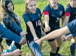  ?? Photograph­s by Gabriella Angotti-Jones Los Angeles Times ?? DALIA HURTADO, center, and the Garfield High soccer team huddle in January. With her mother and siblings in Mexico, she’s turned to sports as she tries to find her way in the world.