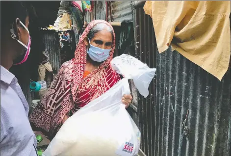  ??  ?? A woman walks home with a food package distribute­d by Mission Save Bangladesh.