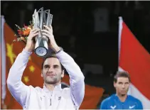  ?? AP-Yonhap ?? Roger Federer of Switzerlan­d lifts his trophy after defeating Rafael Nadal, right, of Spain in their men’s singles final match to win the Shanghai Masters tennis tournament at Qizhong Forest Sports City Tennis Center in Shanghai, China, Sunday.