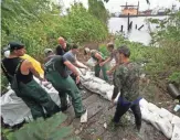  ?? GERALD HERBERT, AP ?? Volunteers stack sandbags Wednesday in Lafitte, La., to prepare for Tropical Storm Cindy’s torrential rain and high winds.