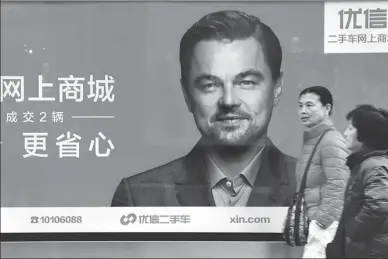  ?? MA JIAN / FOR CHINA DAILY ?? Pedestrian­s pass by a poster of Youxin, an online used car dealer, on a Beijing street on March 9. The poster featuring Hollywood icon Leonardo DiCaprio publicizes Youxin’s online shopping mall.