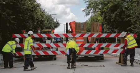  ?? Photos by Godofredo A. Vásquez / Staff photograph­er ?? A Public Works crew closes the exit from Spur 527 to Brazos Street in downtown Monday. The bridge is 50 years old, and officials said it had to be “closed immediatel­y to protect the community from falling debris.”
