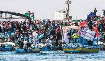  ?? AFP ?? Activists attend an event on a pier in Gaza City harbour for the launch of a blockade-busting boat carrying Palestinia­n students and others injured during protests, surrounded by boats with Hamas’ marine police, to protest Israel’s naval blockade of...