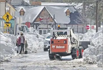  ?? Brian van der Brug Los Angeles Times ?? THE STREETS of Big Bear Lake are still choked with snow after successive storms blanketed communitie­s in the San Bernardino Mountains. Road crews are clearing berms that are 10 feet high in some areas.